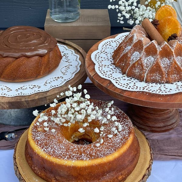 Three Brazilian bundt cakes, one with chocolate, one with powdered sugar and baby's breath, and one with oranges and cinnamon.