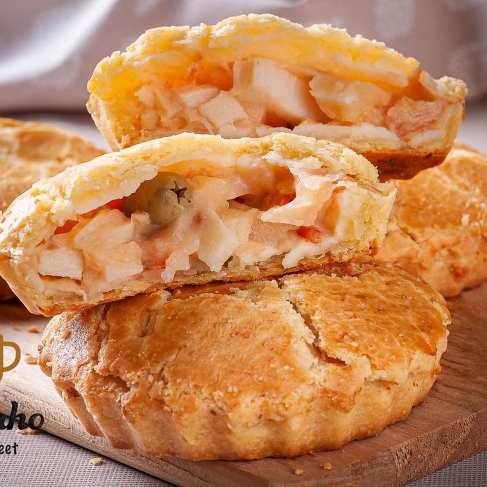 A Brazilian chicken pot pie, or empada de frango, cut in half to show the creamy filling.